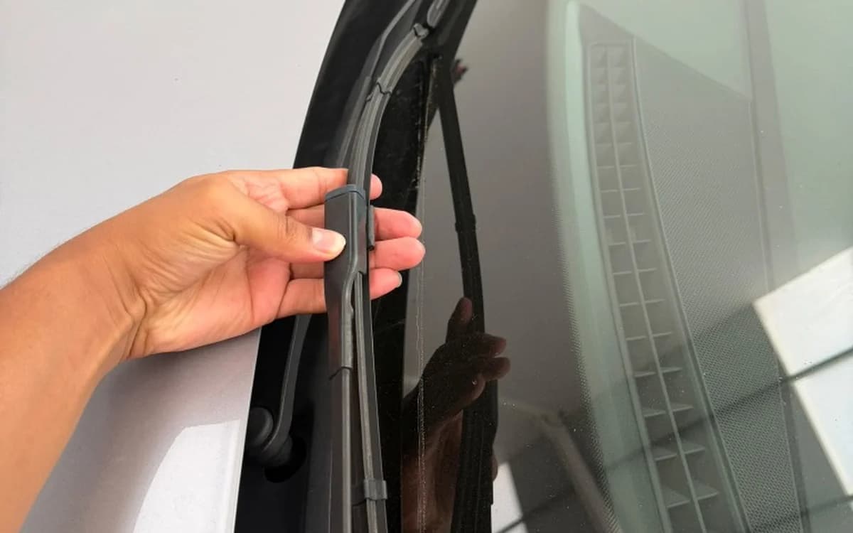 Mano cambiando la escobilla del limpiaparabrisas en el cristal de un coche en Avalon.