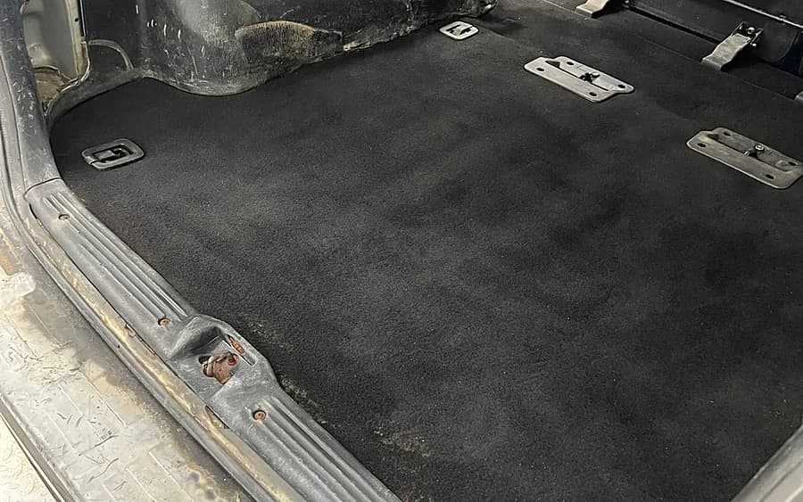 Maletero de un coche vacío y limpio, con la moqueta a la vista.