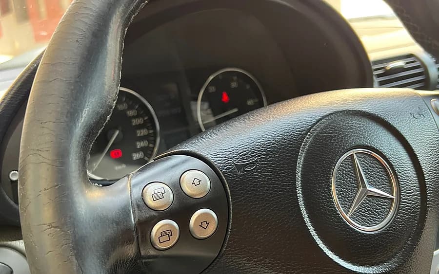 Volante de cuero pelado y agrietado antes de retapizar, con el salpicadero al fondo.