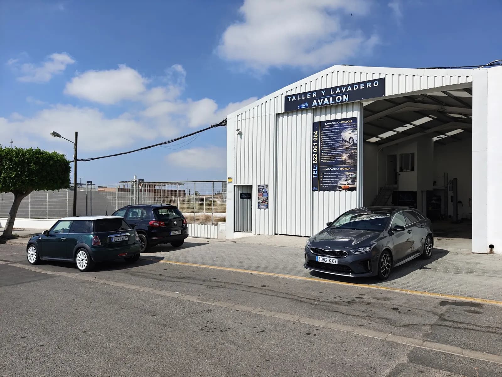 Fachada del taller y lavadero Avalon en El Ejido: nave blanca con el rótulo Taller y Lavadero Avalon, la puerta abierta y coches aparcados delante.